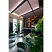 Interior of a cafe with green velvet chairs, terrazzo floor, orange bookshelf, and large Monstera plant.