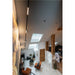 Interior view of a modern loft with skylights, track lighting, stone wall, and orange armchairs.