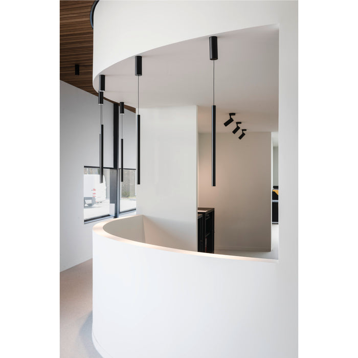Modern interior with black cylinder pendant lights, ceiling mounted, and black track lighting.