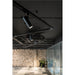 Modern office interior with black track lighting system and cylindrical spotlights.
