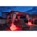 Outdoor patio with metal gazebo, white curtains, lounge chair, dining set, and red glowing sphere lights.