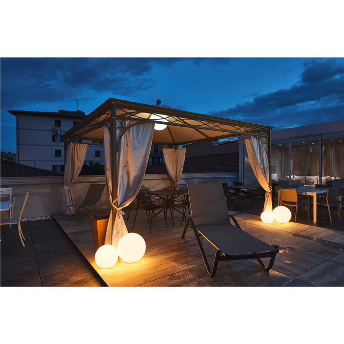 Outdoor rooftop patio with metal gazebo, white curtains, lounge chair, and round floor lamps.