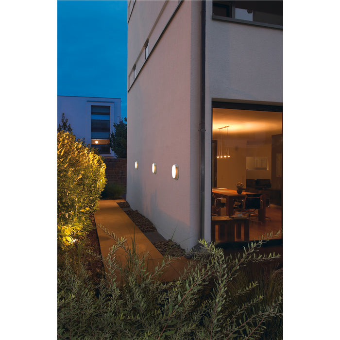 White round LED outdoor wall light fixtures mounted on a modern building.