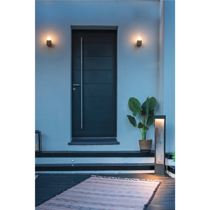 Exterior lighting: Wall-mounted sconces flank a modern gray door with a long silver handle, plus a wood and metal path light.