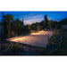 Outdoor bocce ball court with wood frame and gravel fill, illuminated at dusk.